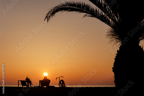 silhouette of the relaxing girl on the sunset beach