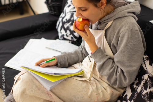 Girl takes notes and snacks on an apple