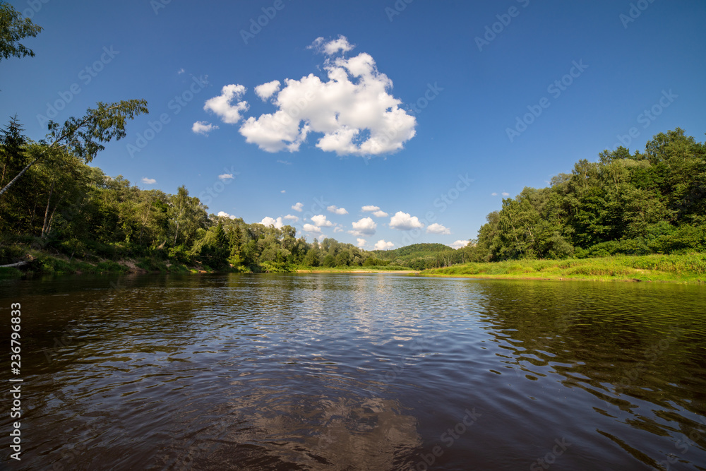 water stream in river of Amata in Latvia with sandstone cliffs, green foliage