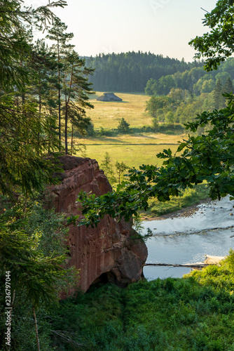 water stream in river of Amata in Latvia with sandstone cliffs, green foliage