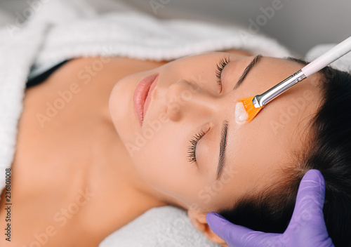 young woman getting a face mask, facial cleansing facial treatment at spa salon