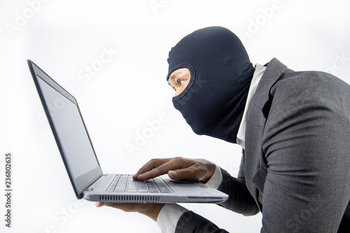 Concentrated trained masked computer hacker at stealing data from computer.