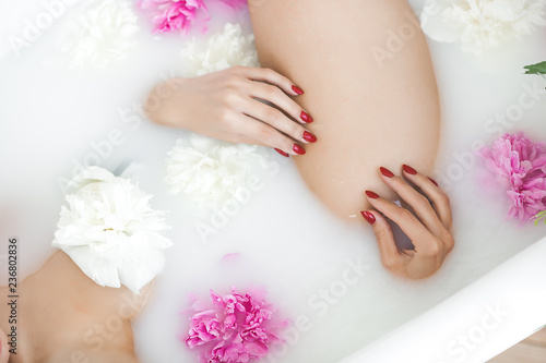 Young beautiful woman taking bath with milk and flowers
