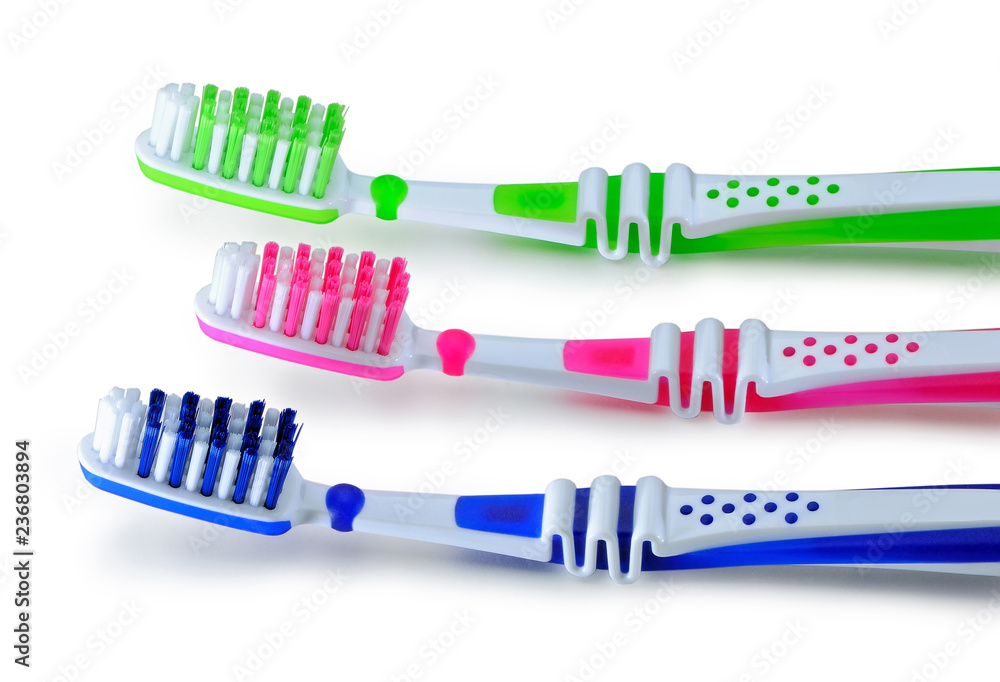 Green, blue and pink toothbrushes are isolated on a white Green, blue and pink toothbrushes are isolated on a white