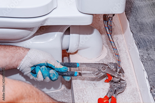 Obraz na plátně Residential repair, replace the valve valve, plumbing closeup, hand red plumbing pliers