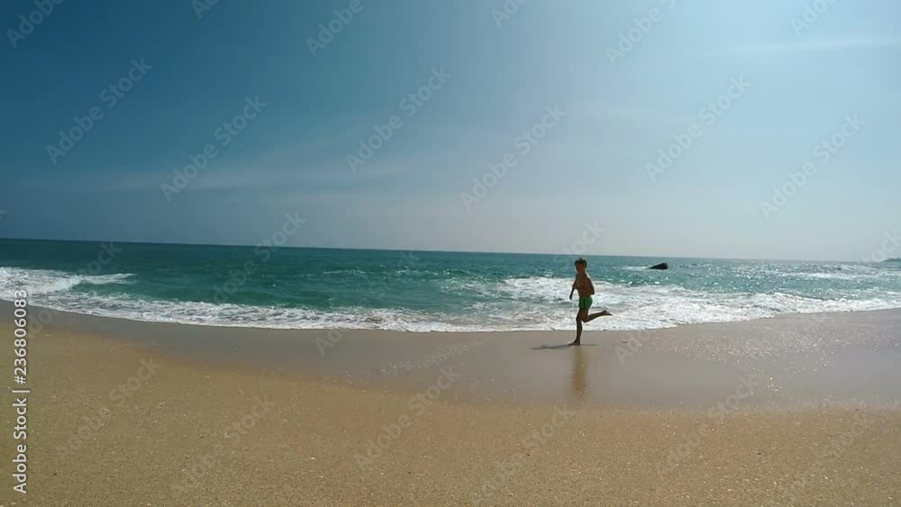 Wide angle shot of little boy running along a wide sandy beach on the Indian Ocean coast line slow Motion footage. Wide angle shot of little boy running along a wide sandy beach on the Indian Ocean coast line slow Motion footage.