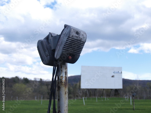 Vintage Drive In movie speakers on a pole with rundown screen in background