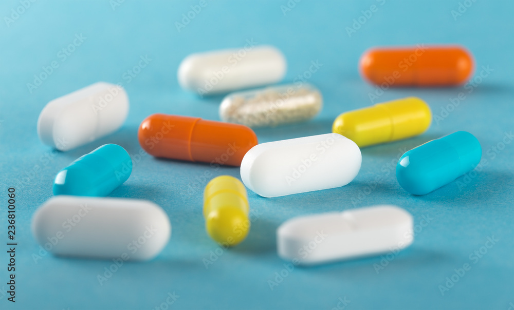 Assorted medical pills and capsules on blue background . Assorted medical pills and capsules on blue background .