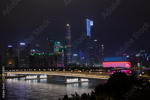 Night modern city with skyscrapers. Bridge over the river  city buildings glow at night. The sky in the clouds hides the building. Travel to China Guangzhou City.