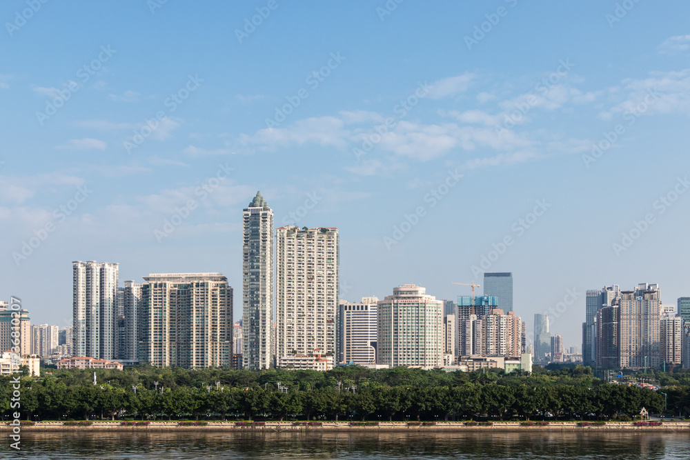 Modern city with skyscrapers. City buildings, a bridge across the river, driving cars on the bridge. High towers of a business center. Modern architecture of buildings.