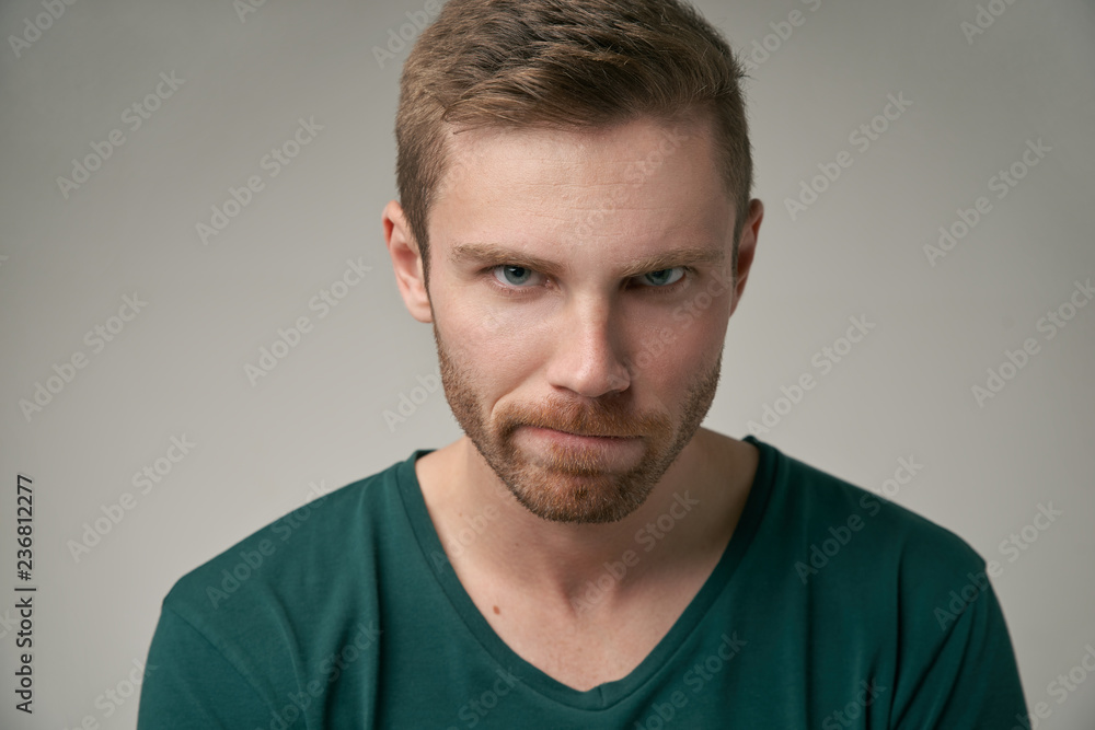 Fototapeta premium angry sullen young man in a t-shirt looks hard at the camera and frown. the concept of bad mood failure disorder. large Studio portrait on isolated background