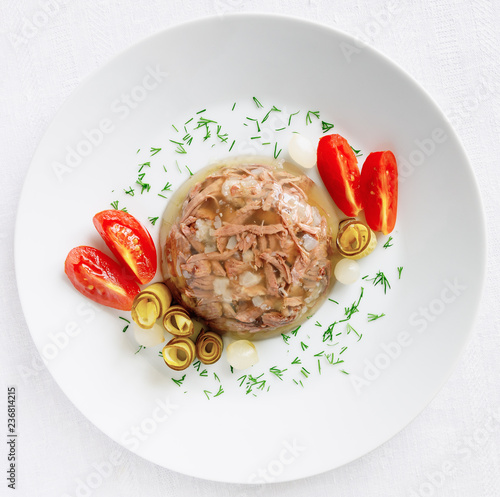 holodets decorated with pickled tomato, onion, and cucumber and sprinkled with dill photo