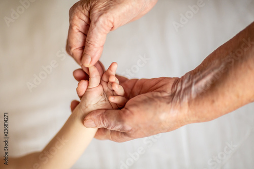 old grandmother hands holding newborn hand, fourth generation family life. the concept of a family and a new life into a selective focus