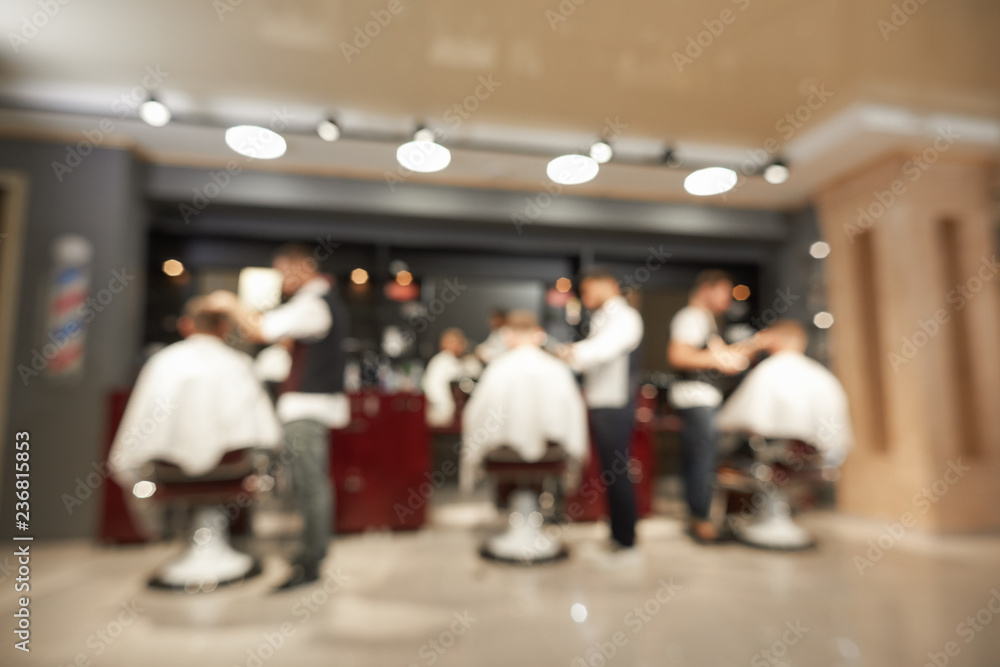 View from back of barbers doing haircuts to male clients View from back of barbers doing haircuts to male clients