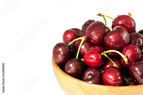 Ripe sweet cherry in wooden bowl isolated on white background closeup.