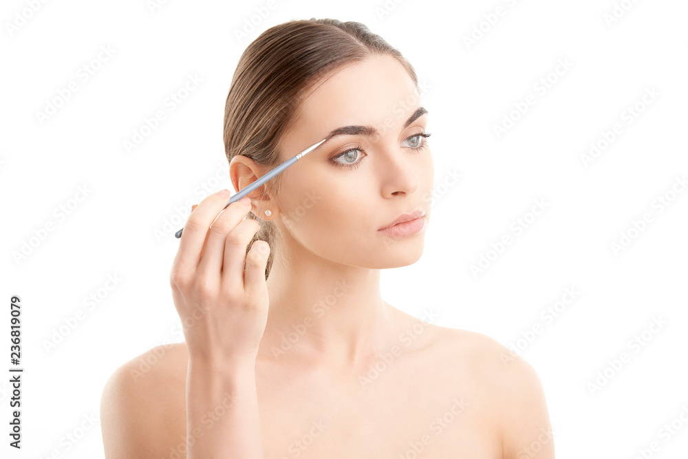 Young naked woman applying makeup. Studio shot.