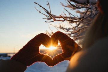 Heart shape symbol of the women mittens in winter frosty sunset. Concept of winter, dating, valentines day and love
