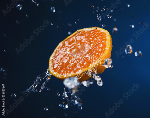 Half of a juicy Mandarin in the spray of water
