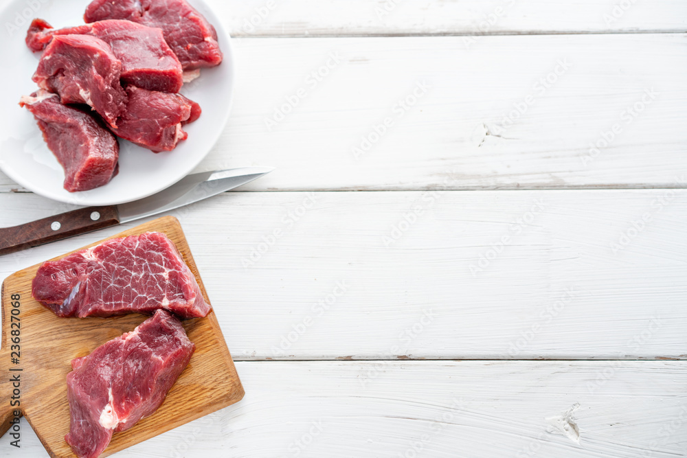 Raw meat. Raw fresh beef steak on a wood cutting board and Carving knife.  White wooden background, top view, copy space, Daylight Stock Photo
