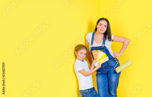 mom and daughter paint the walls in the room, stand near the wall and choose a color for painting