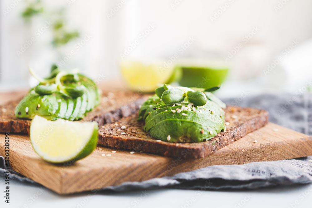 Two toasts with avocado on a wooden board on a breakfast table. The concept of vegetarian and healthy diet food. Two toasts with avocado on a wooden board on a breakfast table. The concept of vegetarian and healthy diet food.