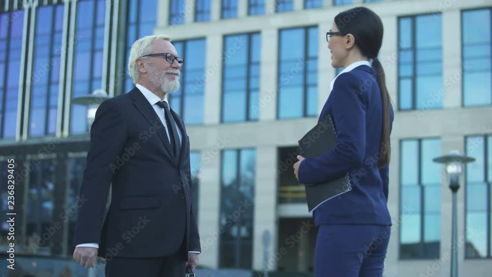 Two business people shaking hands outdoors, merger and acquisition agreement Two business people shaking hands outdoors, merger and acquisition agreement