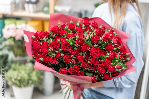 Fototapeta Naklejka Na Ścianę i Meble -  Big luxury bright bouquet in the hands of a cute girl. One hundred of garden red spray roses. Color passionately scarlet, Autumn mood