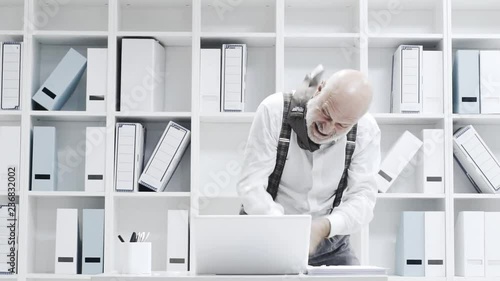 Stressed businessman smashing his laptop with a bat