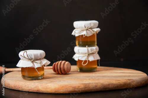 three glass jar with honey isolated on black background