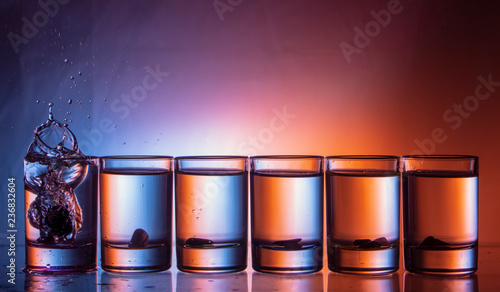 splashing fluid in a glass. That row of glasses on a blue-red background