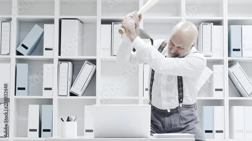 Stressed businessman smashing his laptop with a bat