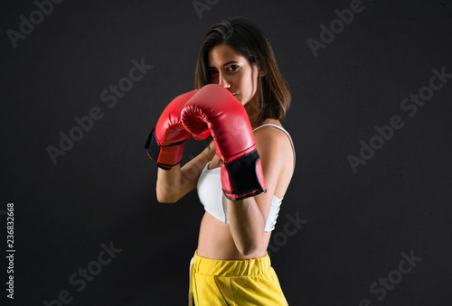 Sport woman with boxing gloves on black background