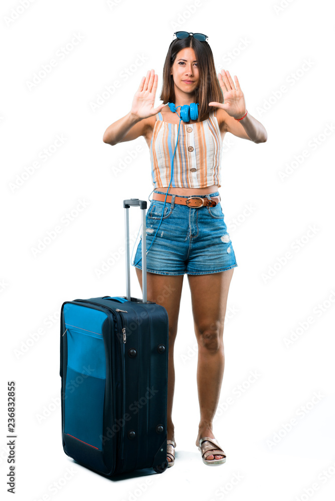 Full body of Girl traveling with her suitcase making stop gesture with her hand denying a situation that thinks wrong on isolated white background Full body of Girl traveling with her suitcase making stop gesture with her hand denying a situation that thinks wrong on isolated white background
