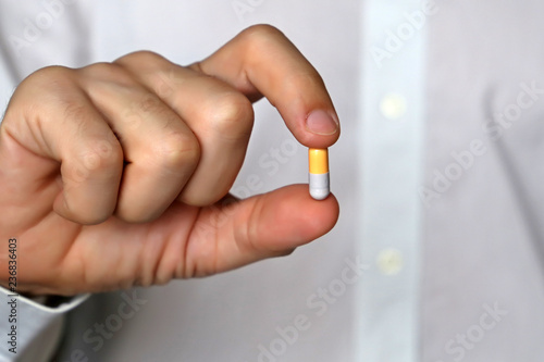Doctor holding pill, male hand with medication in capsule close-up. Man with tablet, concept of pharmacist, drugs, diet pill, antibiotics or vitamins