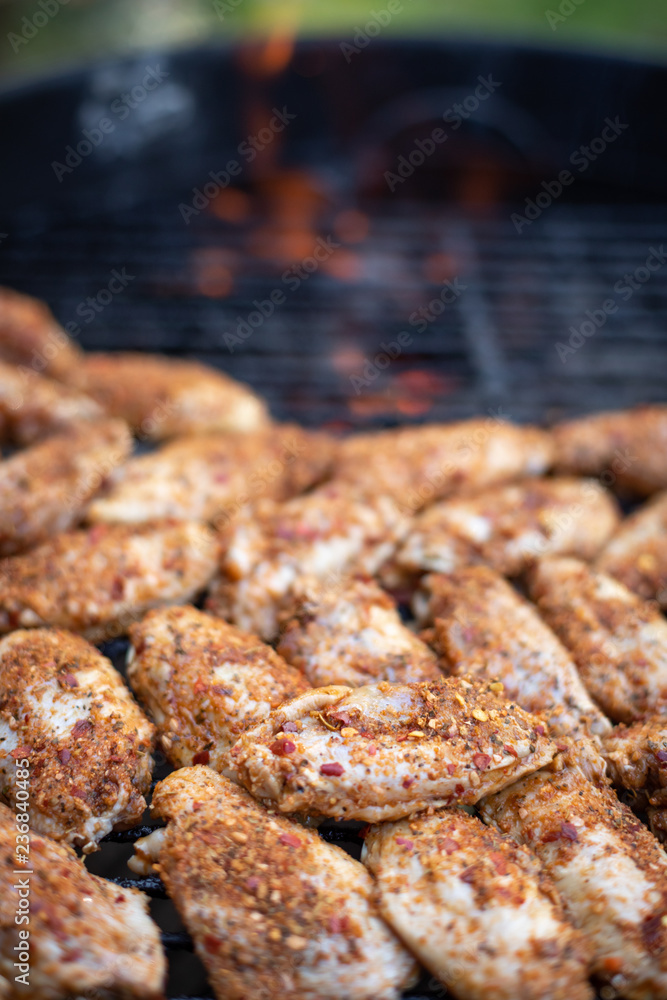 Close up on raw chicken wings grilling on a barbecue, with space for text on top
