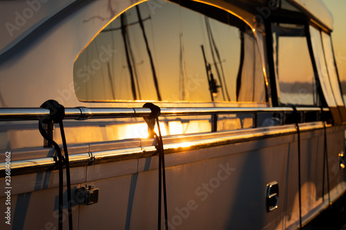 Side close up on a a luxury yacht reflecting a sunset
