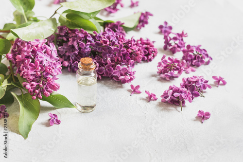 Glass jar with rose water and lilac flowers, space for text. Close up. Concept for spa and aromatherapy.