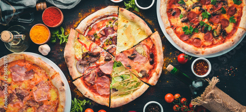 A set of Italian pizza. Italian cuisine. On a black wooden background. Free copy space. Top view. photo