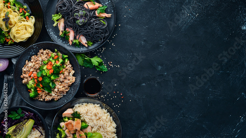 A set of food and dishes. Pasta, rice, risotto, salad. On a black background. Free copy space.