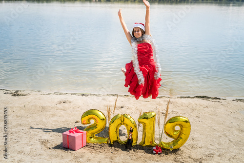 Girl in santa hat jumping on the beach photo