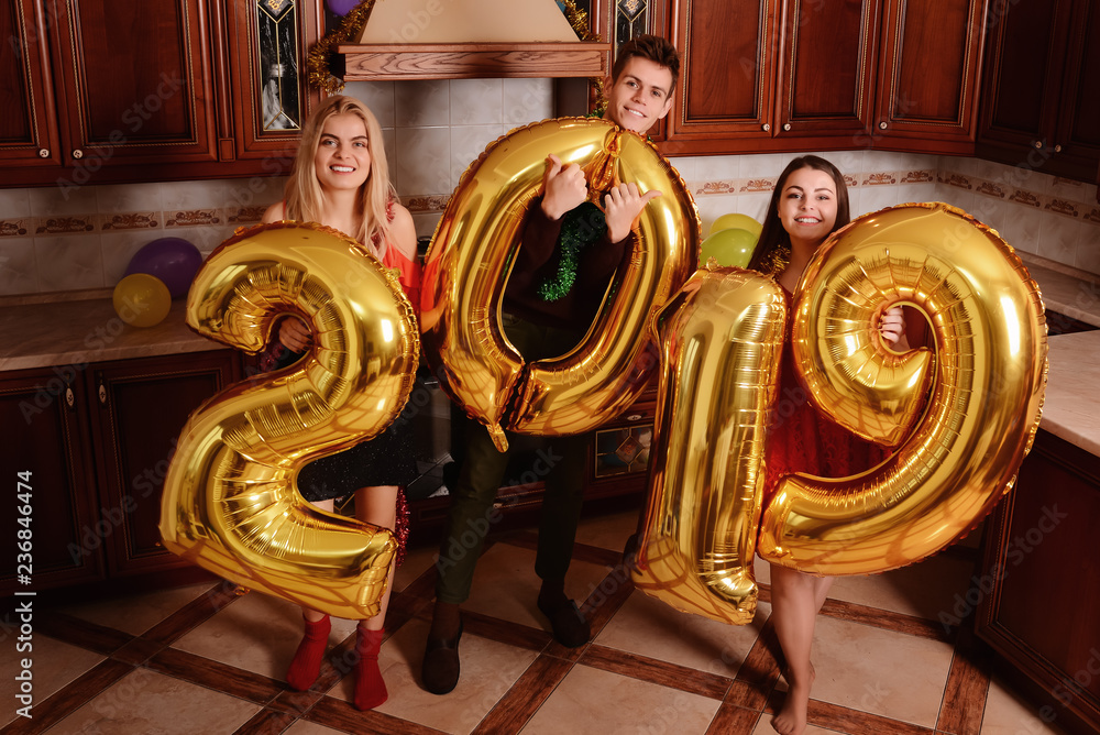 New 2019 Year is coming. Group of cheerful young people carrying gold colored numbers and have fun at the party