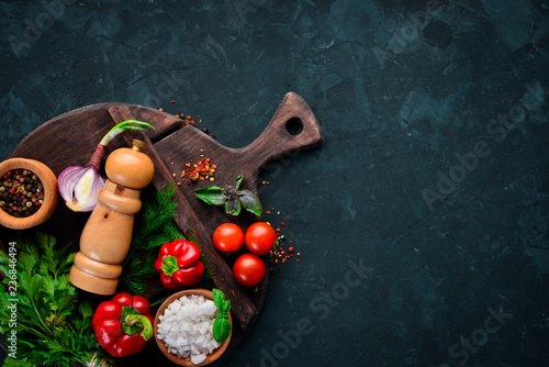 Vegetable background. Fresh tomatoes, paprika, onions and parsley on the table. Top view. On a black background. Free space for text.