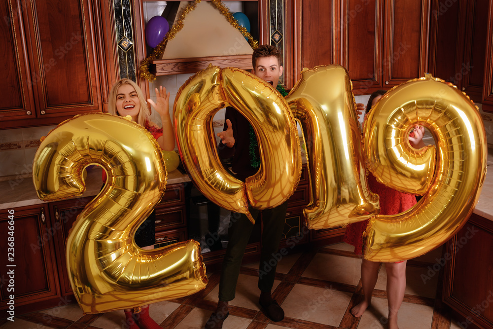New 2019 Year is coming. Group of cheerful young people carrying gold colored numbers and have fun at the party