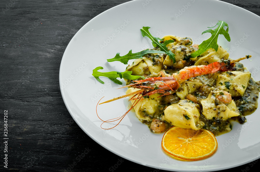 Ravioli with shrimp and seafood. Italian cuisine. Dumplings. In a plate on a wooden background. Top view. Free copy space. Ravioli with shrimp and seafood. Italian cuisine. Dumplings. In a plate on a wooden background. Top view. Free copy space.