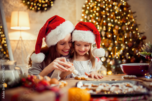 Merry Christmas and Happy Holidays. Family preparation holiday food. Mother and daughter cooking Christmas cookies. © zamuruev