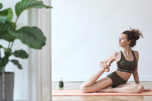 Young darkhair, active woman exercising and stratching on the floor at her studio. Healthy lifestyle, home training, mental balance.