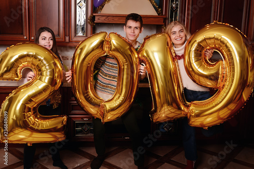 New 2019 Year is coming. Group of cheerful young people carrying gold colored numbers and have fun at the party