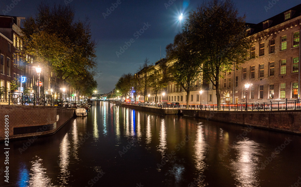 Nighttime on a canal in Amsterdam with a full moon