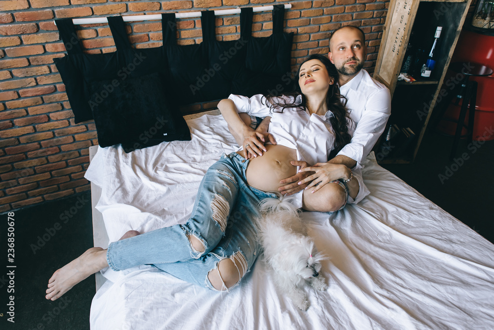 Couple in love pregnant lie in bed cuddling, waiting for baby