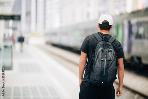 Young traveler man with backpack in the railway at train station. travel concept.